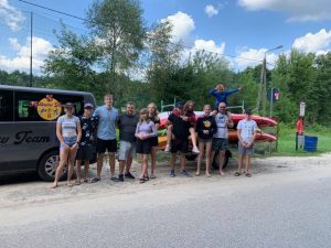 Grupa osób przy przyczepie z kajakami.